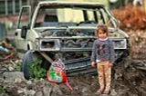 Girl standing in a war-torn area.