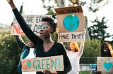 a young climate change activist in nice black shirt with a placard saying “Go Green”