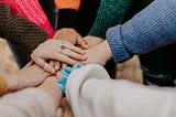 A group of people bringing their hands together, signifying unity