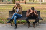 woman and man sitting on a bench after having an argument