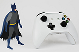 Batman standing next to a white Xbox controller.