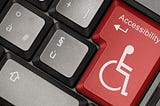 Recorte de um teclado, com a tecla maior ,  onde usualmente fica a tecla “enter”, em vermelho, com um boneco branco usando cadeira de rodas, e o texto “Accessibility” em cima, que significa “acessibilidade” em inglês.