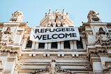 Picture of a banner hanging from a building with the words: Refugees Welcome