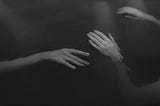 Image shows Grayscale Photo of Hands Floating on Water