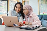 two females sitting looking at a laptop together