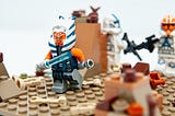 Lego figure of Star Wars character Ahsoka Tano holding a lightsaber and running.