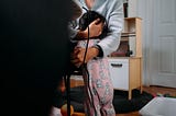 Woman seated at a desk with a computer on it comforting a toddler in pink pajamas