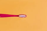 Red toothbrush on contrasting orange background