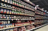 The soup aisle in a grocery store, depicting several shelves with cans of various soups.