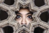 shocked woman’s eyes peeking through wood carved wall opening