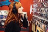 Young woman listening to music and looking at CDs in a music shop