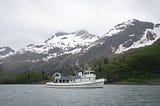 Research vessel Island C in cove with snow covered mountains in the background.