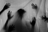 A transparent sheet with the silhouette of a head and multiple hands trying to reach through to the other side.