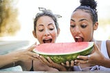 Women gorging on a huge chunk of watermelon