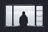 A person sitting alone watching outside the window pane