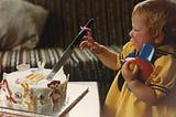 One-year-old baby in yellow dress cuts birthday cake