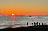 Brillant orange sunset over the ocean with people watchin