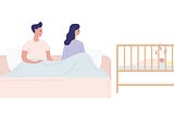 A couple sits in bed looking over at their sleepless baby in a crib.