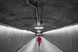 Person wearing red jacket and backpack in a subway