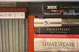 Various plays and books about Shakespeare in tight focus on a bookshelf.