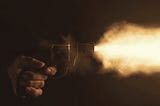 A revolver being fired in the dark.
