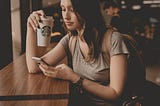 A woman drinking Starbucks and checking her text messages on iPhone