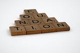 Scrabble letters stacked in a pyramid, spelling out ‘FOUNDATION’