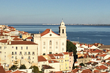 Red-roofed white houses in Lisbon, with the sea in the background