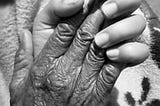 An old person’s hand in a young person’s hand.