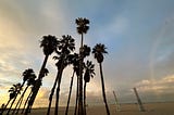 Palm trees, beach, rainbow, and interesting clouds in Santa Monica, CA.