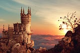 A castle sits on a cliff above the clouds at sunset.