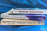 Stack of three paperback books: The Left Hand of Darkness by Ursula K. Le Guin, The Color Purple by Alice Walker, and The Sound and the Fury by William Faulkner.