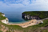 View of North Landing, Flamborough, Yorkshire, UK — chalk headlands either side with sandy bay on a sunny day.