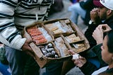 Person holding a cardboard box with food packs for people.