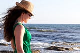 A contented looking woman at the beach wearing a green dress