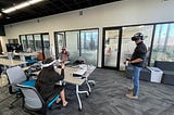 Three people using VR headsets, their faces covered and their hands gesturing in the air to interact with the virtual world they are experiencing