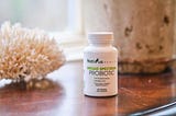A bottle of Nativus Health Broad Spectrum Probiotic on a table next to a window with beautiful light coming in