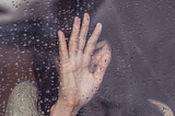 sad woman leaning against glass window