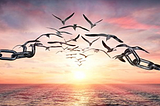 The open ocean spread with the golden rays of the evening sun, the sun is visible on the horizon where the sky touches the sea. A heavy chain, broken in the middle while its broken pieces turns into birds flying freely towards the sun.