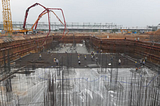 A photograph of many workmen pouring the concrete foundation for a very large building.