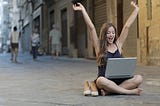 A woman enjoying watching her laptop while sitting on the floor.