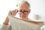 Man with glasses reading the newspaper
