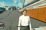 Starfield NPC Helena Chambers stares disapprovingly into the camera, while the player’s customizable spaceship sits on a hangar platform in the background over her right shoulder.