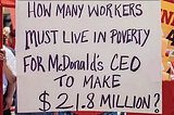 Protest Sigh that reads: How Many Workers must live in poverty for McDonalds CEO to make 21.8 million?