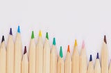 Photo by Jess Bailey on Unsplash showing a line of brightly colored pencils lined up at different heights