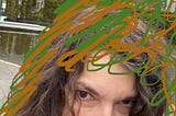 Close up selfie photo of the top half of my head, just showing my eyes, and lots of green and brown scribble on my hair and around my head.