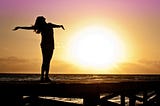 Happy woman arms outstretched during sunset