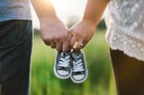 Couple linked by holding baby shoes