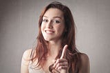 Smiling woman pointing up her index finger