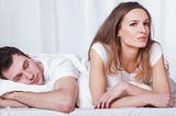 couple in bed man sleeping pensive woman